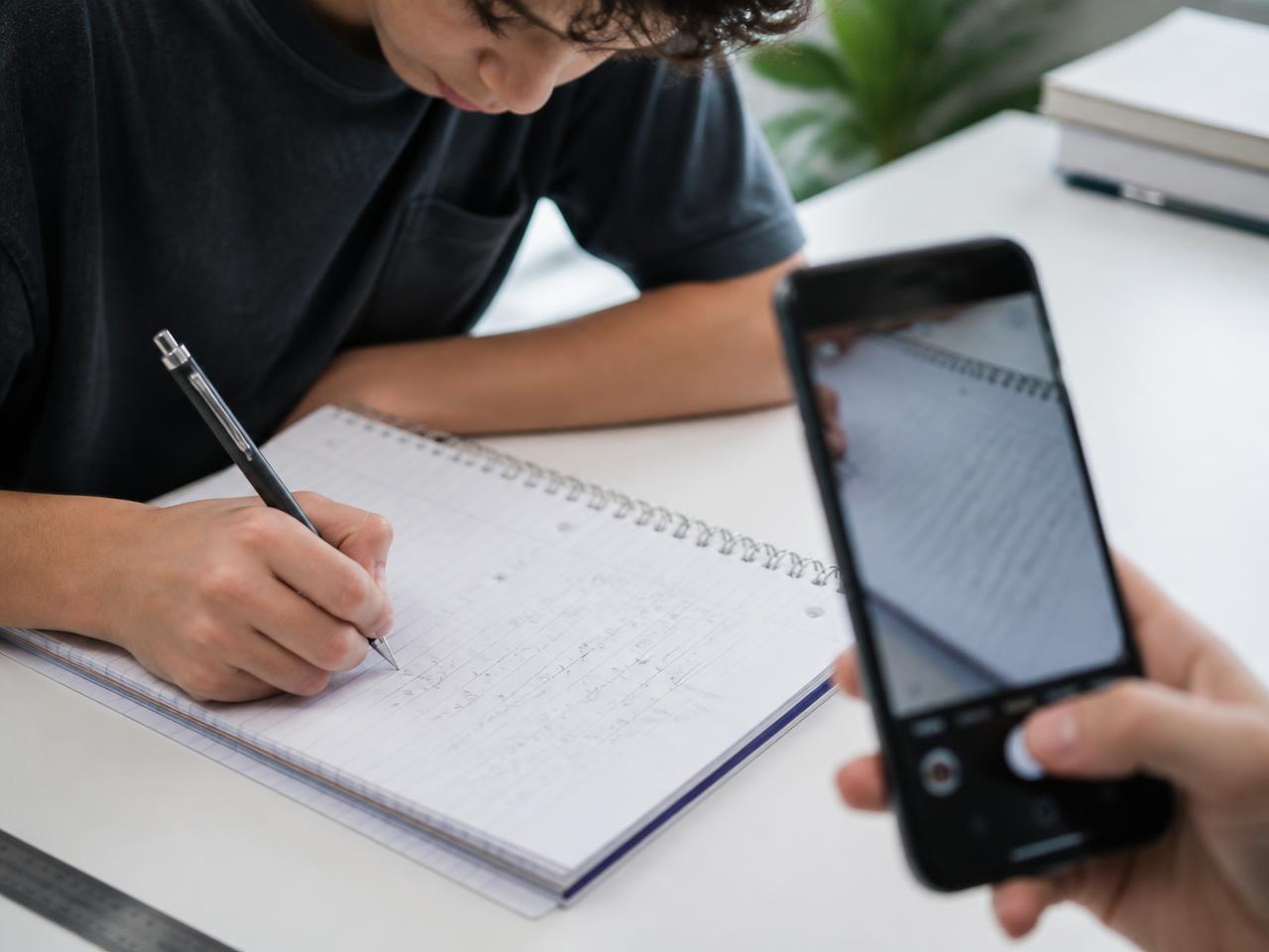 A student photographing handwritten working to submit it
